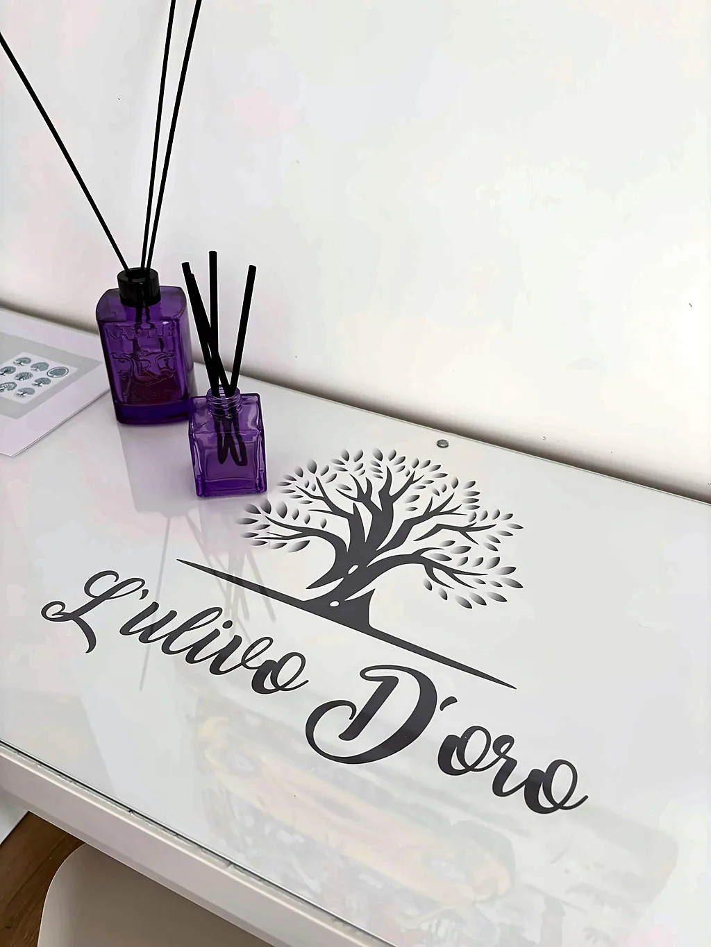 La scrivania con il logo di L'Ulivo D'oro e un diffusore di profumo