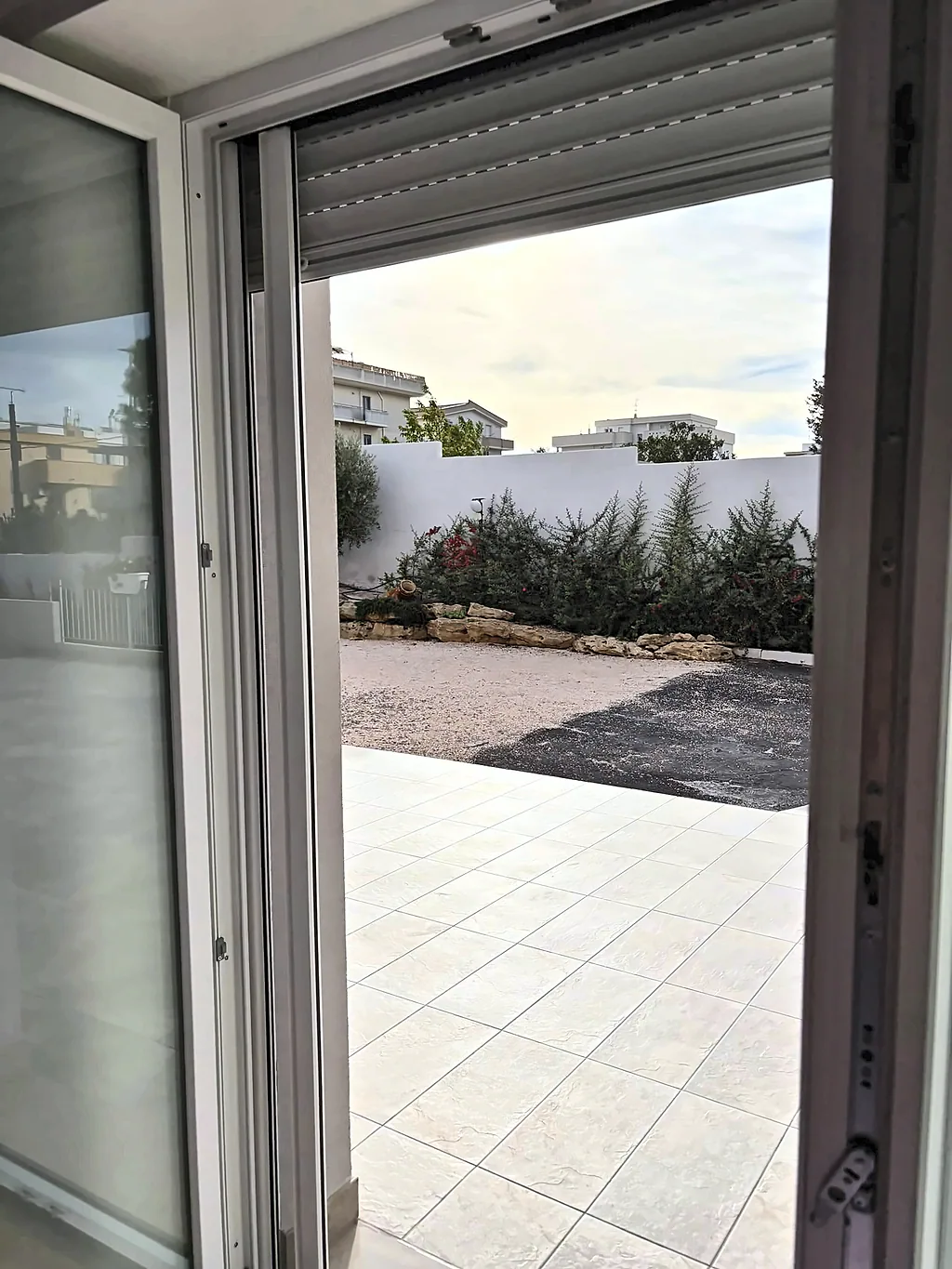 La portafinestra aperta sul patio pavimentato e sul cortile