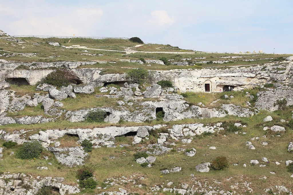 Grotte scavate nella roccia calcarea sull'altopiano del Parco della Murgia Materana, tra erba e massi