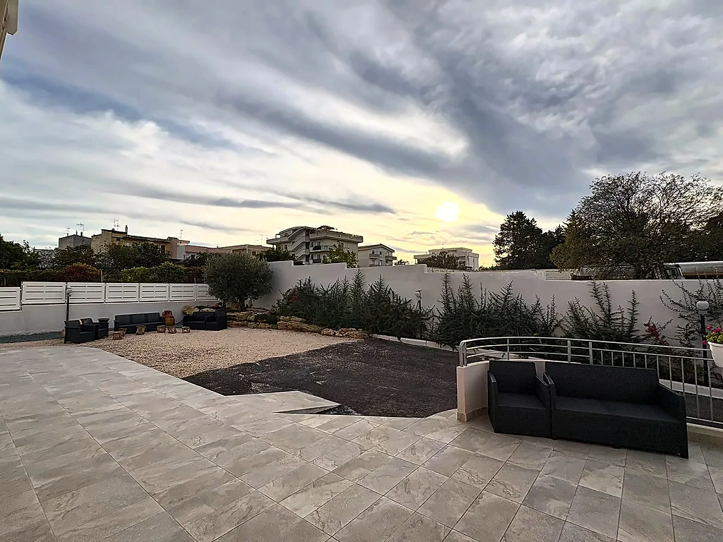 Ampia terrazza pavimentata con un divano da esterno, sotto il cielo del tramonto
