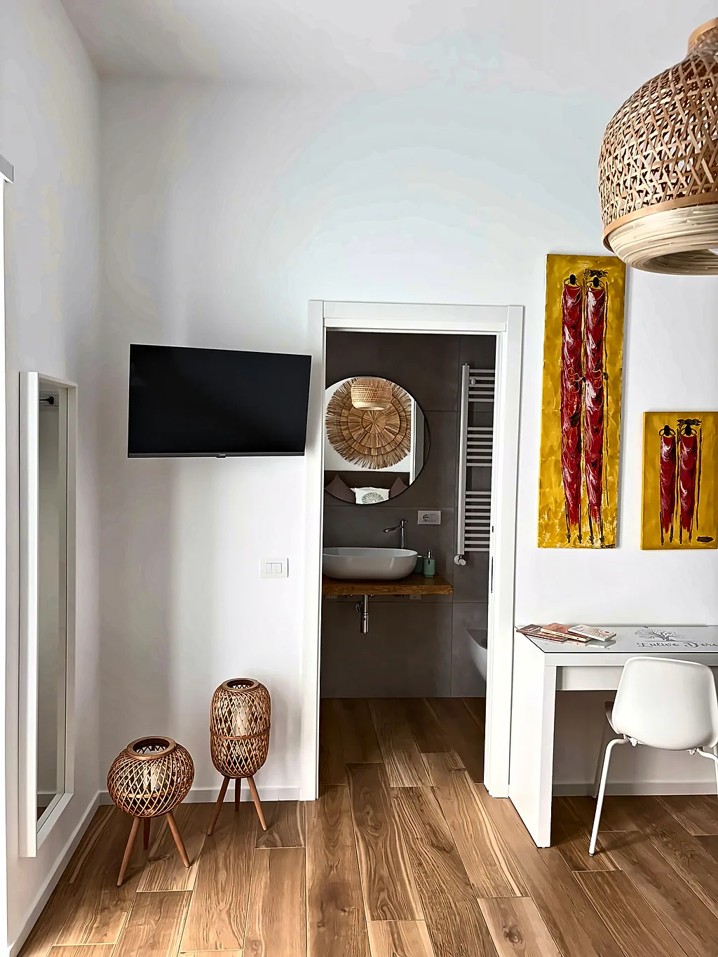 La TV a parete, i quadri e la porta aperta sul bagno