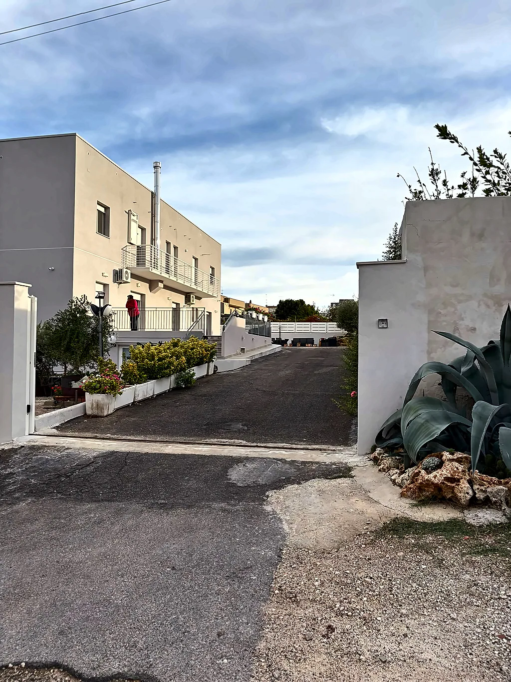 L'ingresso carrabile: il cortile all'interno del cancello, con la casa sulla sinistra e le piante lungo il muro
