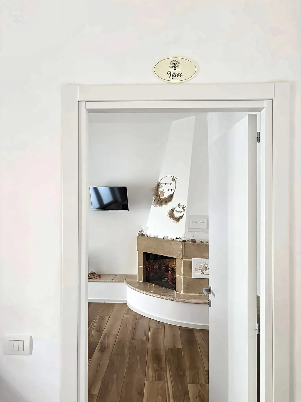 L'ingresso della camera Ulivo, con la targhetta sopra la porta e il camino in pietra sullo sfondo